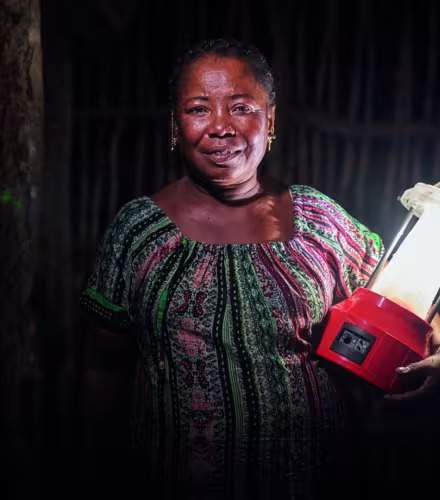 Portrait de Kingeline, une ingénieure en énergie solaire, tenant une lampe solaire.